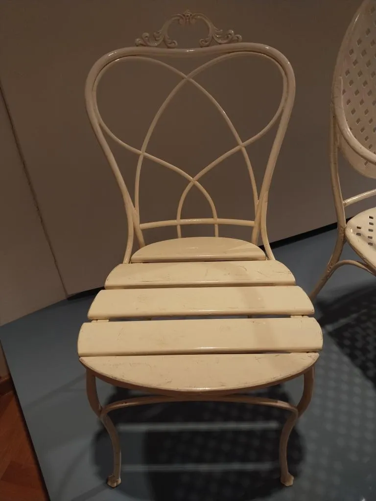 Light-colored Thonet garden chair with curved metal backrest and slatted seat, showing the patented construction introduced in 1891.