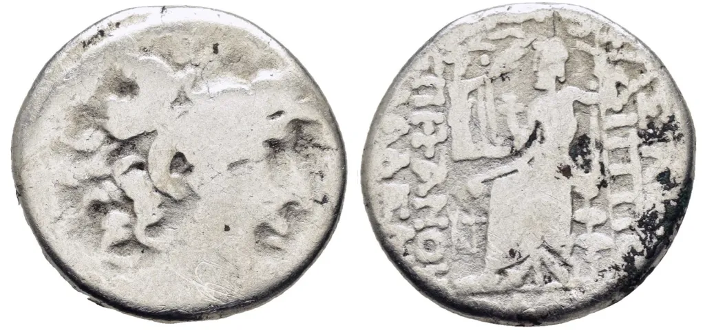 Vorder- und Rückseite einer griechischen Silber-Tetradrachme des Antiochos IV Epiphanes aus Syrien; die Vorderseite zeigt den bärtigen Kopf des Zeus nach rechts, die Rückseite Zeus Nikephoros nach links auf einem Thron sitzend, mit Nike und langem Zepter, umgeben von griechischer Legende.
