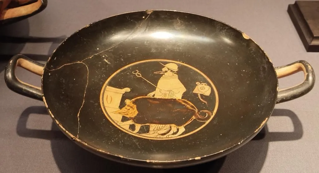 Griechische rotfigurige Kylix mit zwei Henkeln, zeigt Hermes mit Reisehut und Heroldstab, der ein Opferschwein zu einem Altar führt. Um 510–500 v. Chr.
