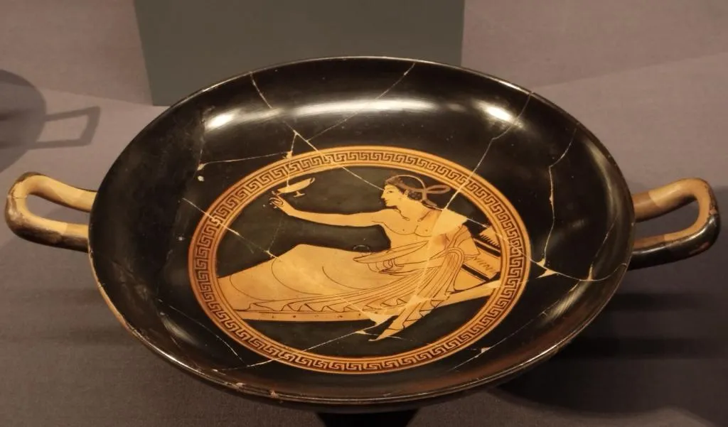 Antike attische rotfigurige Kylix mit zwei Henkeln, im Tondo ein liegender Jüngling beim Kottabosspiel. Datiert auf ca. 500 v. Chr.