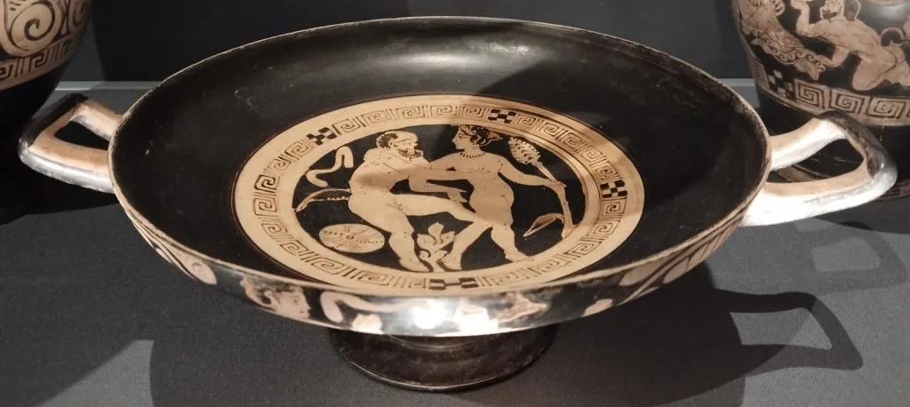 Etruscan kylix with two handles, tondo shows a Silen embracing a Maenad with thyrsus. Made in Caere, Italy, 4th century BCE.