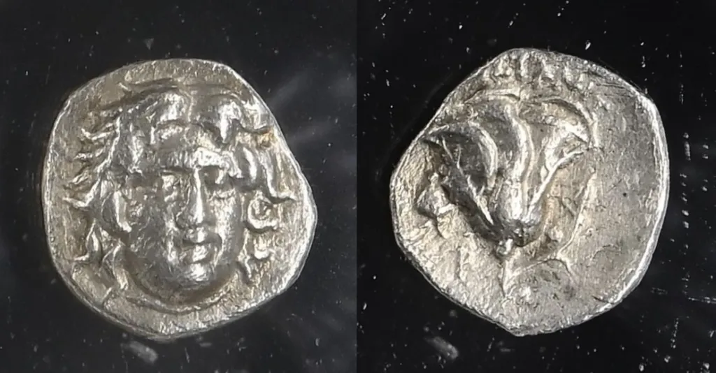 Fotografie einer rhodischen Silber-Tetradrachme in zwei Ansichten vor dunklem Hintergrund, mit dem frontalen Kopf des Helios auf der Vorderseite und einer Rose mit Knospe auf der Rückseite.