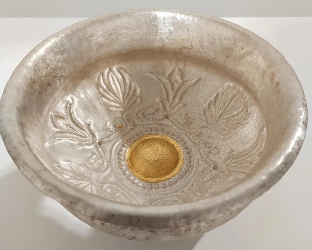 A Roman silver phiale featuring embossed floral motifs and a central gilded omphalos, likely intended for ritual use.