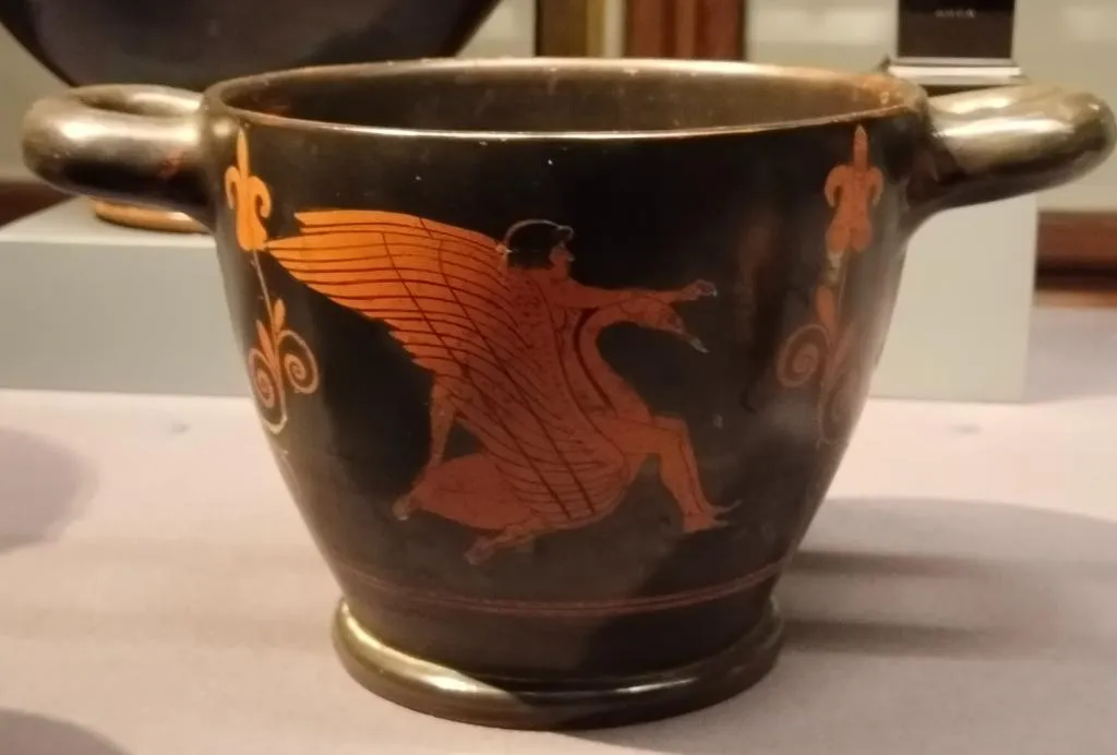 Ancient Greek red-figure skyphos with two handles, showing a winged figure (Zephyros) reaching toward Hyacinth seated on a large swan in motion.