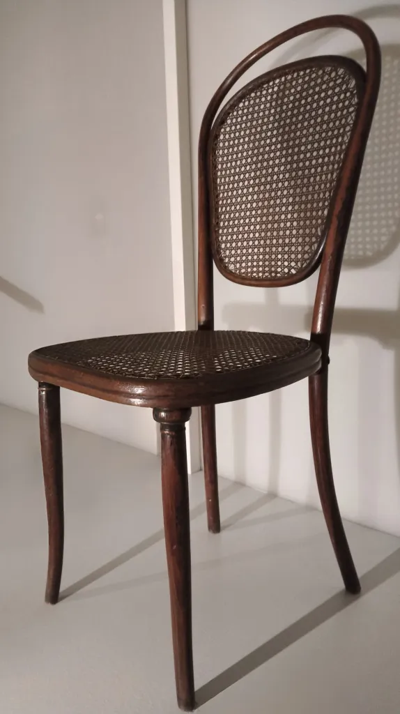 Side view of a Thonet bentwood chair Model No. 12, showing a curved oval cane backrest, cane seat, and subtly flared legs.