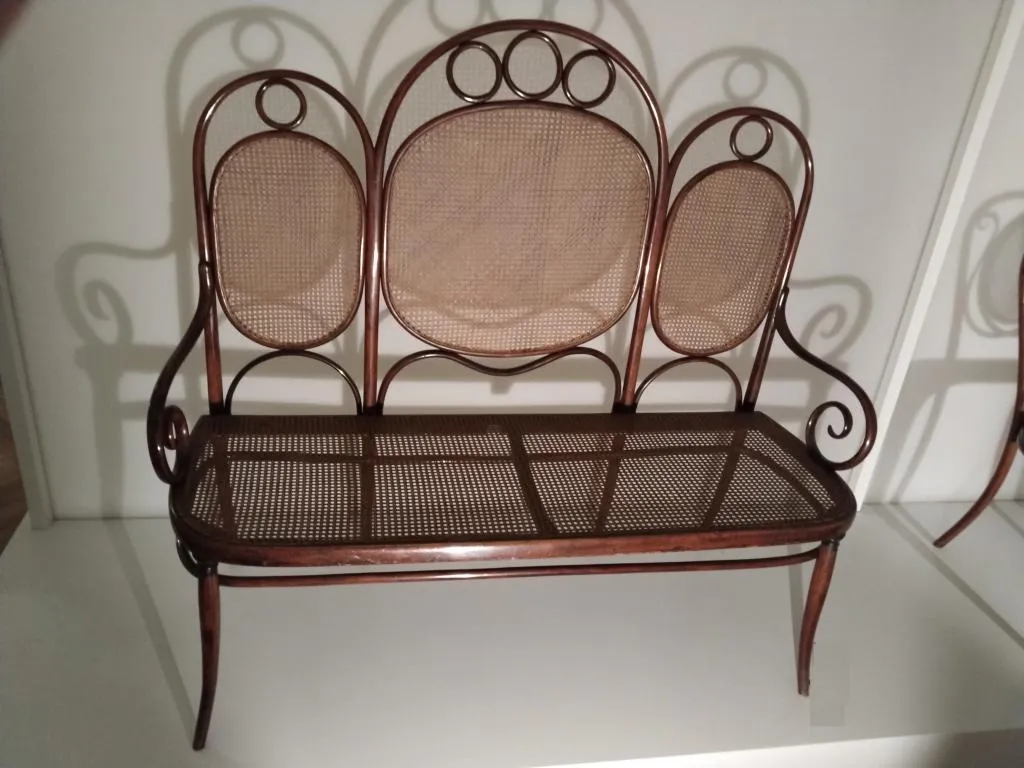 Photograph of Thonet bentwood settee Model No. 17 featuring three oval cane back panels, cane seat, and curved armrests, produced by Gebrüder Thonet in the late 1800s.