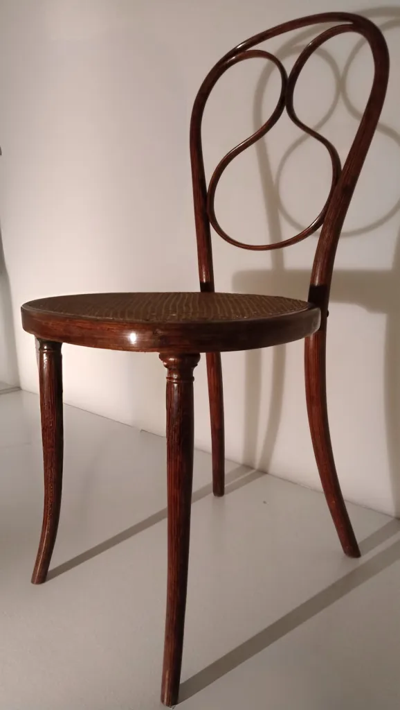 Seitenansicht des Thonet-Stuhls Modell Nr. 1 mit Bugholzrahmen, geschwungener Rückenlehne und Sitzfläche aus Geflecht.