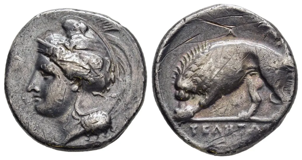 Two-sided image of an ancient Greek silver stater from Velia in Lucania. The obverse shows Athena facing left in a crested helmet ornamented with a griffin-like device. The reverse shows a lion moving left above a ground line, with a short ethnic inscription placed below the type.